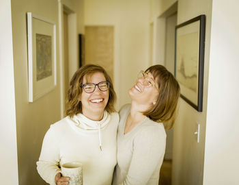 Cheerful sisters standing in corridor at home