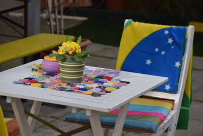 Flower pot on table by chair with brazilian flag in back yard