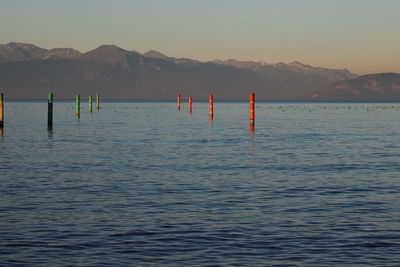 Wooden posts in sea against sky