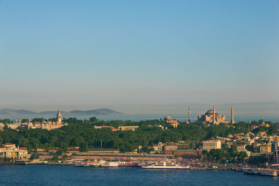 Scenic view of sea by buildings against clear sky