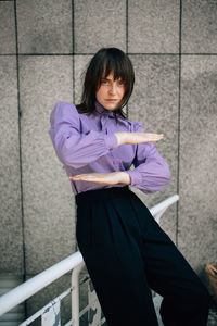 Portrait of woman standing against wall