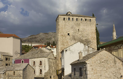 Buildings in city against cloudy sky