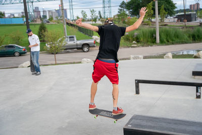 Rear view of man skateboarding on city street