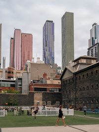 People on modern buildings in city against sky