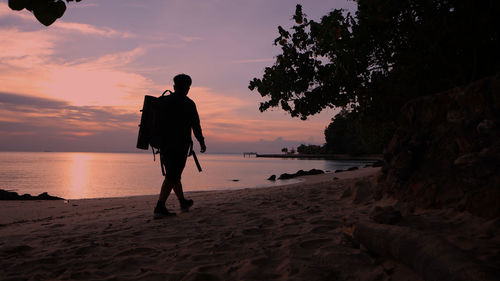 Rear view of man on beach during sunset