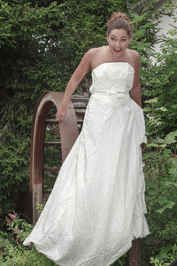 Portrait of bride standing on arch against trees