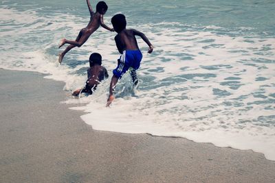 Rear view of people enjoying on beach