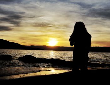 Silhouette woman at beach during sunset