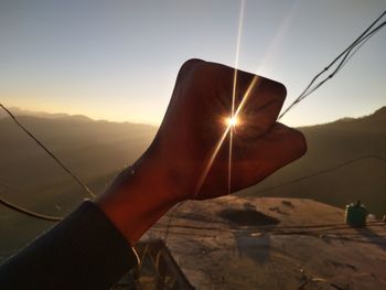 Close-up of hand holding sun at sunset