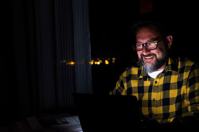 Smiling man using laptop at darkroom