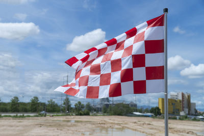 Low angle view of flags against cloudy sky