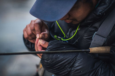 A man ties a fly onto the end of his fishing line on a cold morning