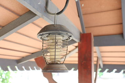 Low angle view of illuminated light bulb hanging on ceiling in building