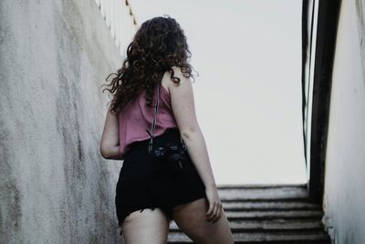 Low angle view of young woman standing by wall