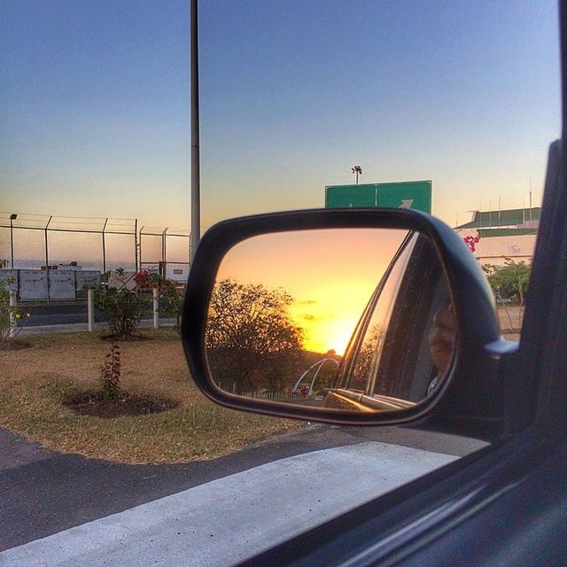 transportation, land vehicle, mode of transport, car, side-view mirror, sunset, road, sky, street, clear sky, reflection, stationary, glass - material, part of, sunlight, no people, transparent, travel, sun, bicycle