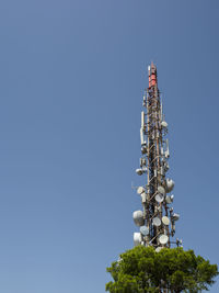 Low angle view of communications tower against clear blue sky