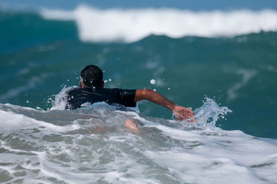 Man splashing water in sea against sky