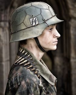 Profile view of young soldier wearing helmet and bullets