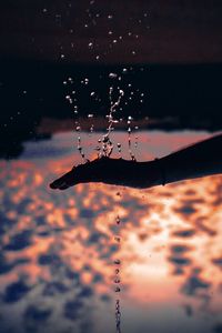 Close-up of silhouette water drop against sky during sunset