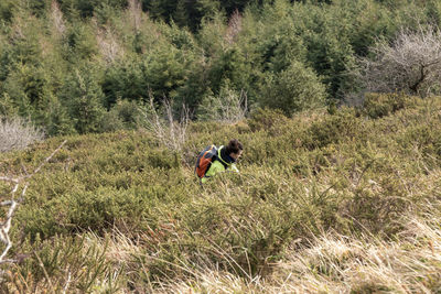 Mountaineer woman climbing a steep slope among the undergrowth