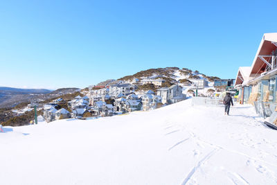 People on snowcapped mountain against clear blue sky