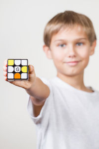 Portrait of boy holding rubik cube over white background