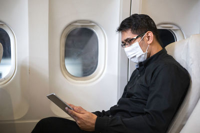 Mature man wearing mask sitting in airplane