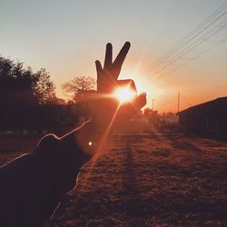 Close-up of silhouette hand against sunset sky