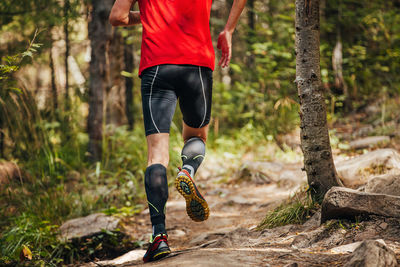 Male runner in compression calf sleeve running forest trail