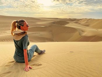 Man standing on sand dune in desert against sky