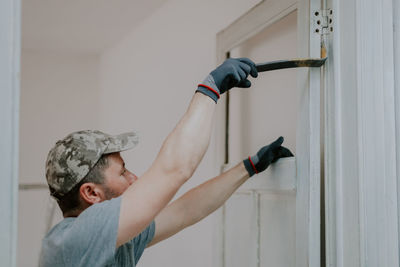 A young man is working with a crowbar in a doorway.