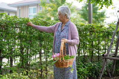 Woman holding umbrella while standing by wicker basket
