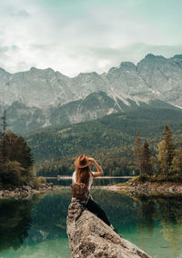 Rear view of woman looking at lake against mountain range