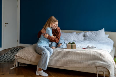 Young woman sitting on bed at home