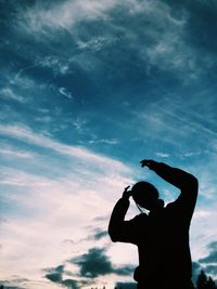 Low angle view of silhouette woman with arms raised against sky