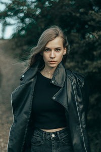 Portrait of young woman standing against trees