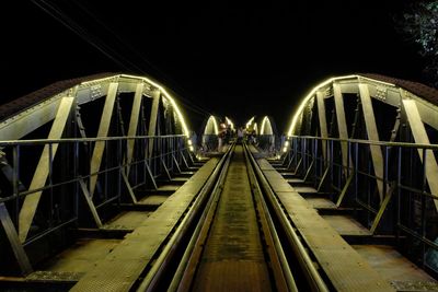 Illuminated footbridge against sky at night