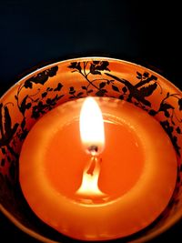 Close-up of lit candle against black background