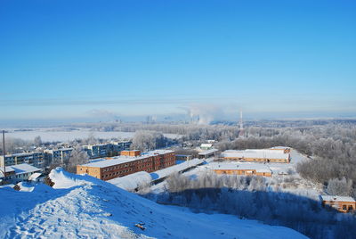 High angle view of houses and snowcapped mountains against blue sky