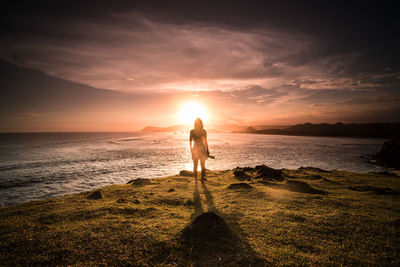 Silhouette woman looking at sea against sky during sunset 