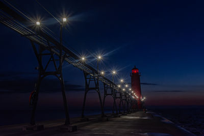 Lights illuminate the grand haven, michigan, pier and lighthouse as the sky turns dark blue