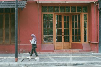 Side view of woman walking on footpath against building