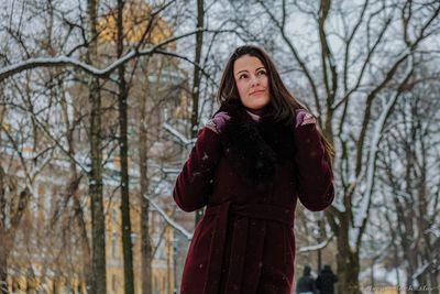 Portrait of young woman standing against trees