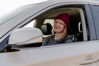 Woman smiling at camera from car at sunset