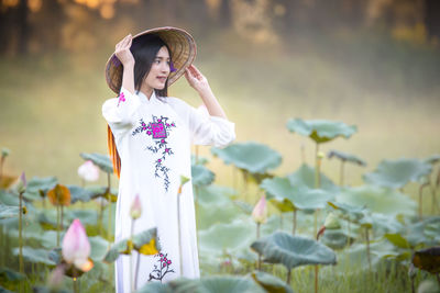 Beautiful smiling woman hat standing amidst lotus buds