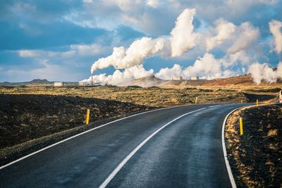 Road leading towards mountains against sky