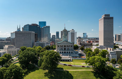 Trees and modern buildings in city against sky