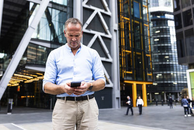 Mature businessman using smart phone at office park