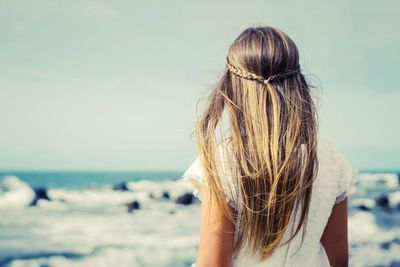 Rear view of woman at beach against sky