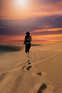 Rear view of woman in desert during sunset